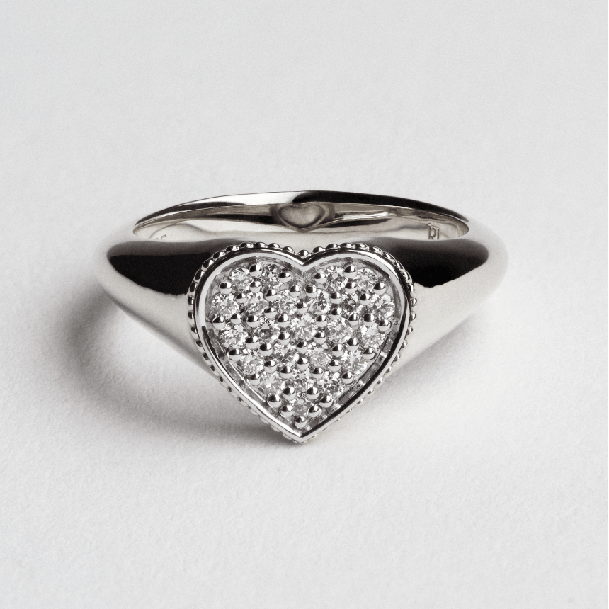Heart-shaped white gold ring with embedded diamonds on a light gray background