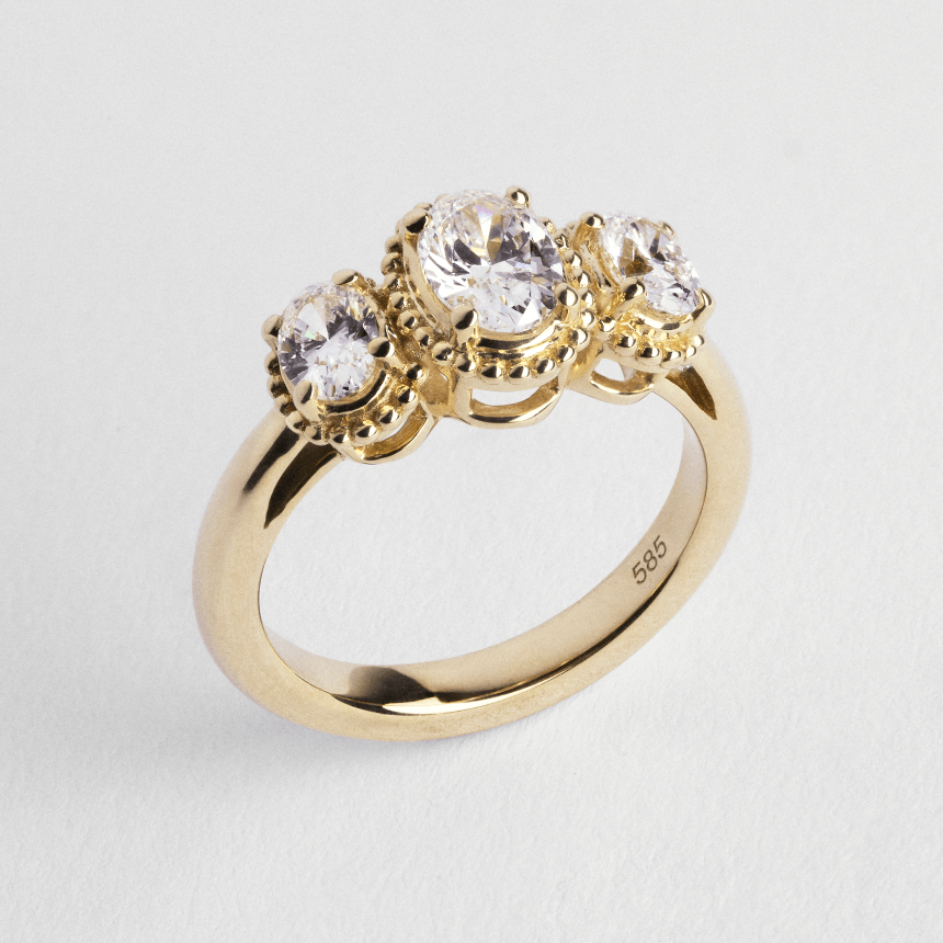 Yellow gold diamond trilogy ring on light grey background