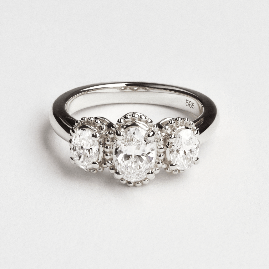 White gold diamond oval trilogy ring on light grey background