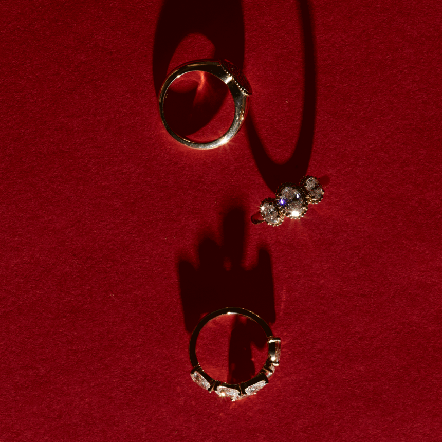 Gold diamond pinky rings on red background
