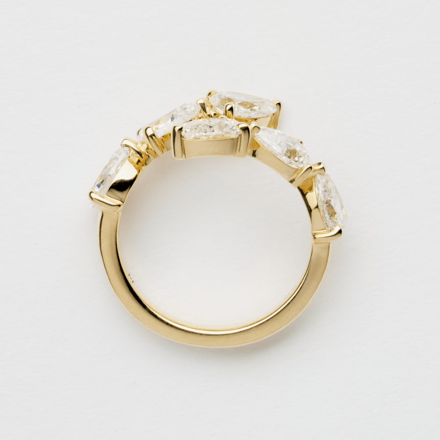 Gold ring with six pear cut diamonds on a light gray background