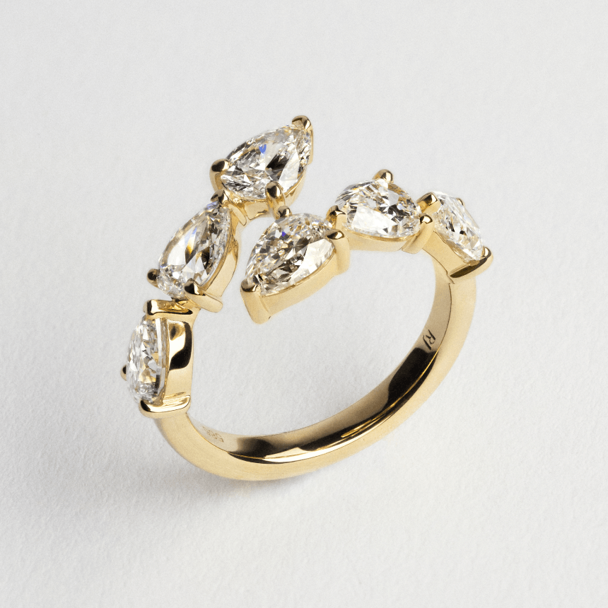 Gold ring with six pear cut diamonds on a light gray background