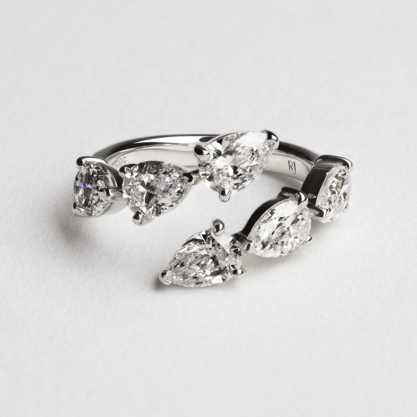 White gold diamond ring with pear-shaped stones on a light gray background