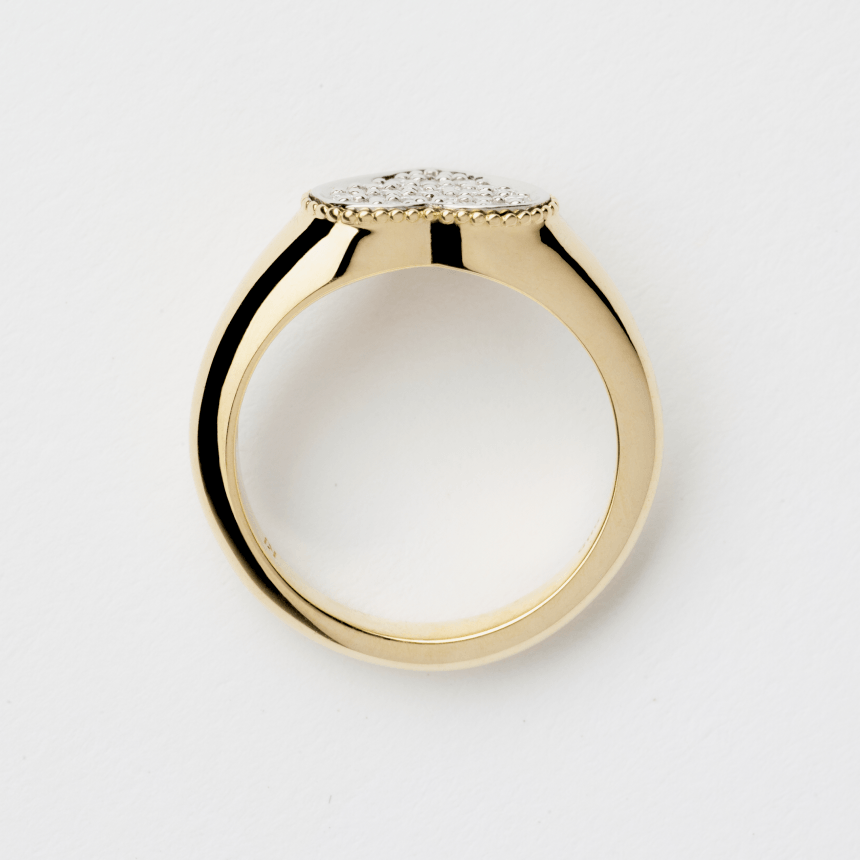 Gold pinky signet heart ring with pave diamonds on a light gray background