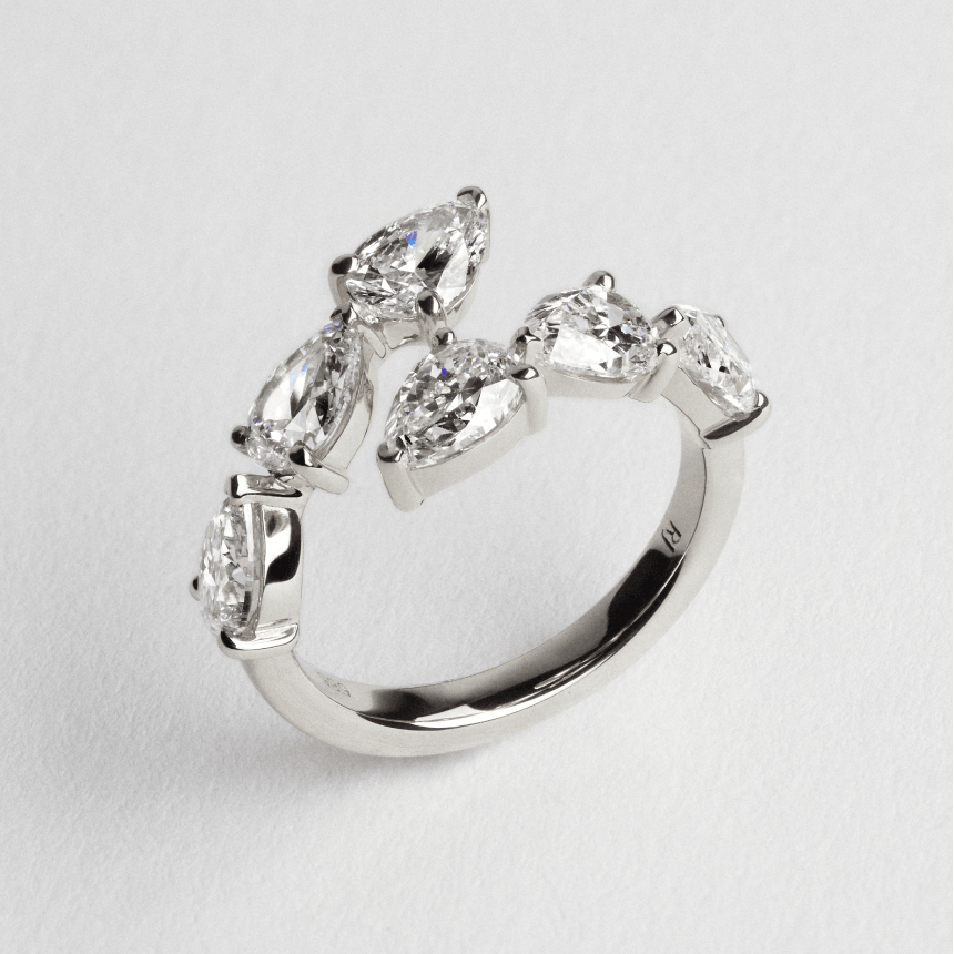 White gold ring with pear-shaped diamonds on a light gray background