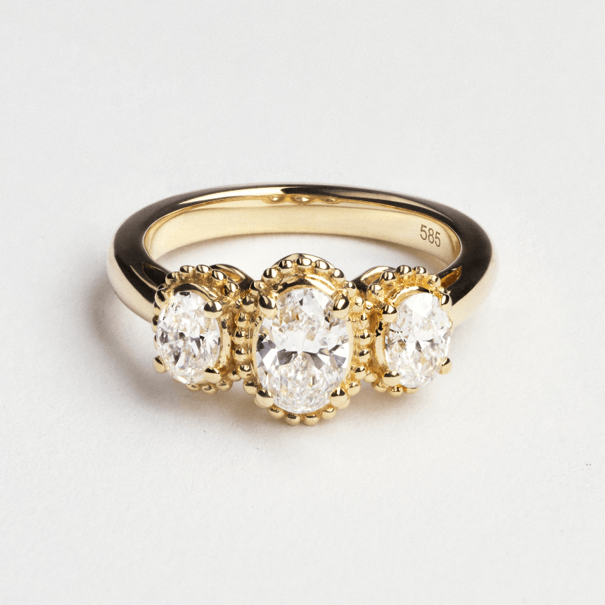 Yellow gold diamond oval trilogy ring on white background