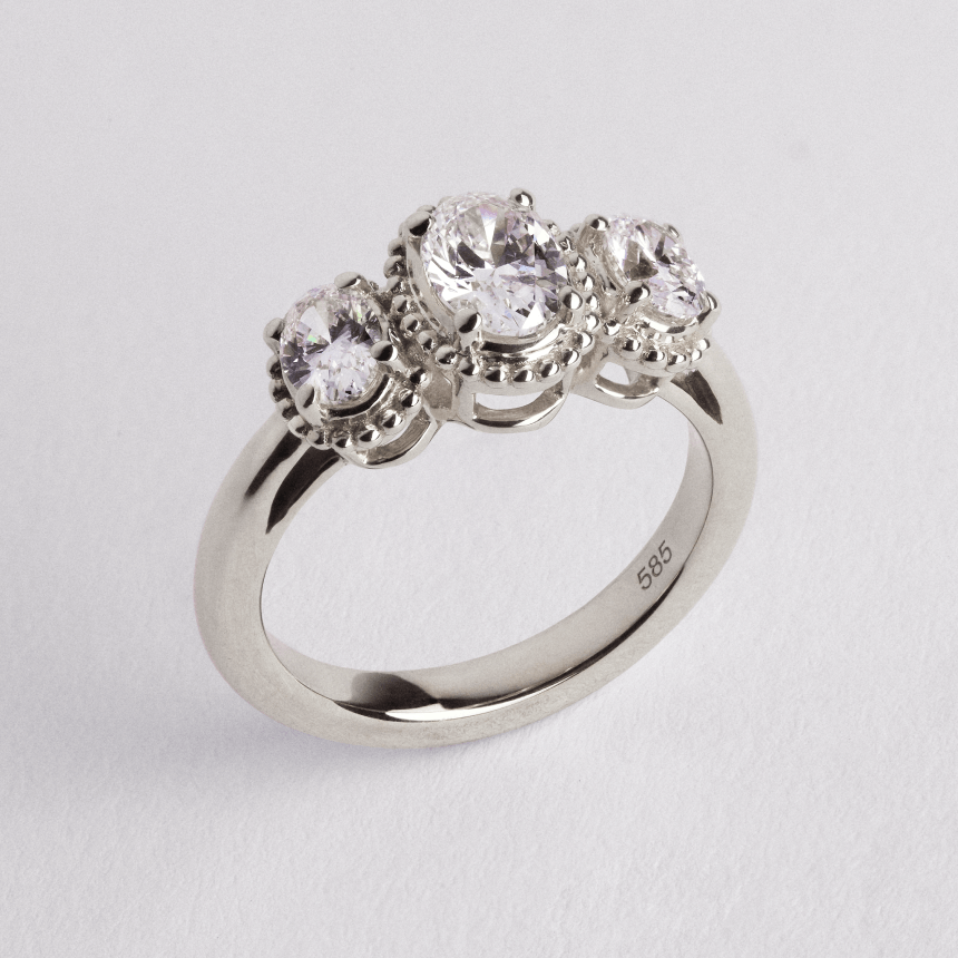 White gold diamond oval trilogy ring on light grey background side view